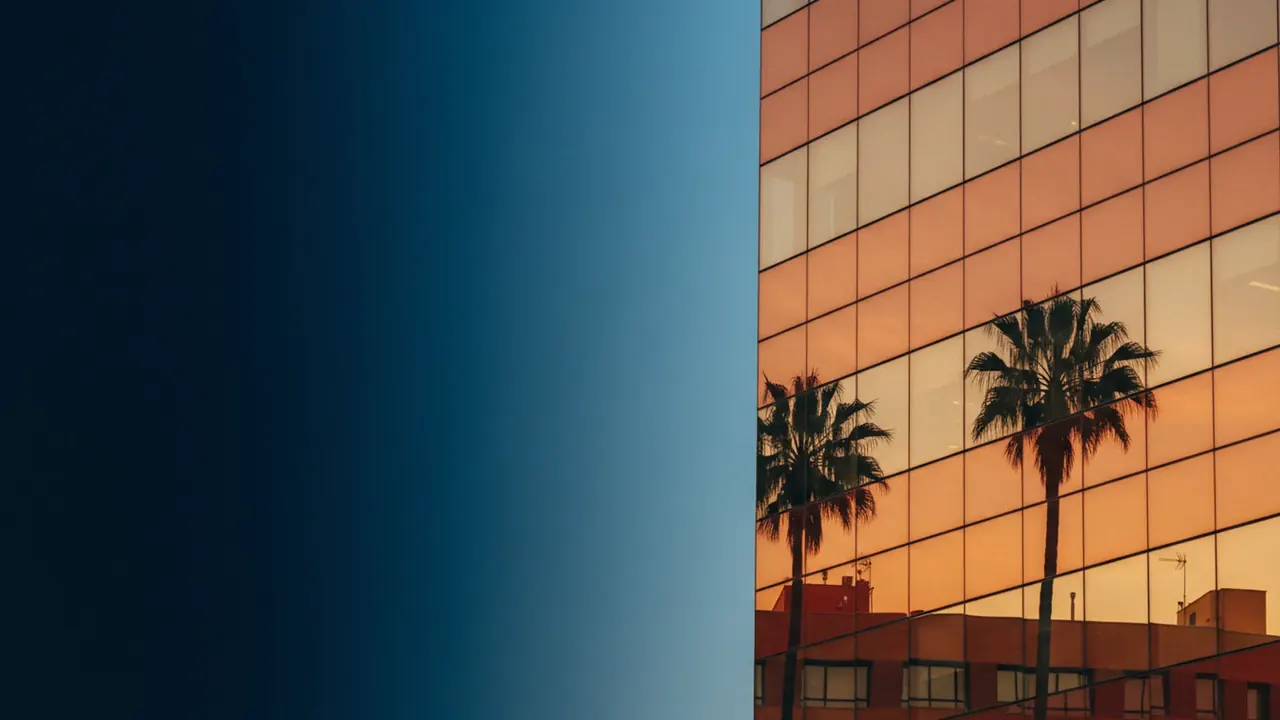 Modern Valencia office building facade reflecting palm trees and warm afternoon sky